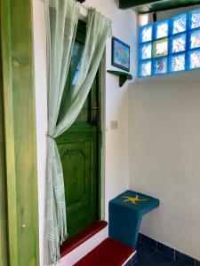 a room with a green door and a blue stool at Holiday Home Case Blu in Lipari