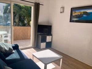 sala de estar con sofá azul y TV en Charming 1 bedroom flat, Biarritz center with pool and car park, en Biarritz