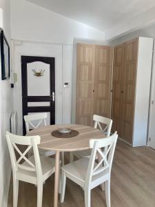 a dining room with a wooden table and white chairs at Charming 1 bedroom flat, Biarritz center with pool and car park in Biarritz