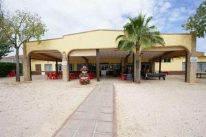 un edificio con una palmera delante en Camping Carlos III, en La Carlota
