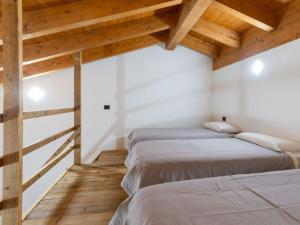 two beds in a room with wooden ceilings at Agriturismo Baita Bavè in San Fedele Superiore