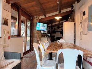 La casa di Sergio في Bauladu: غرفة طعام مع طاولة خشبية وكراسي بيضاء