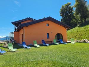 a group of lawn chairs in front of a house at Agriturismo Baita Bavè in San Fedele Superiore