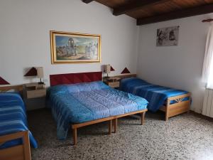 La casa di Sergio في Bauladu: غرفة نوم بسريرين ولوحة على الحائط