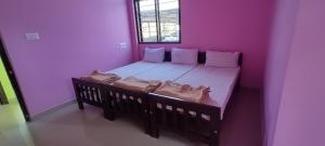 ein kleines Schlafzimmer mit einem Bett mit lila Wänden in der Unterkunft STAYMAKER Madhu Residency in Sāgar