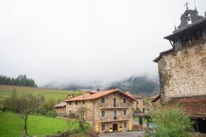 un antiguo edificio de piedra con una montaña en el fondo en Osabarena Hotela, en Murueta-Orozko