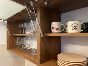 a wooden shelf with cups and glasses and plates at Prestige Apartment Teslic in Teslić
