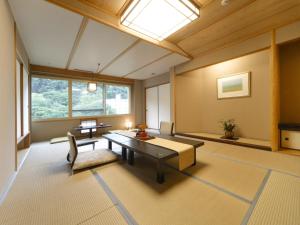 Habitación grande con mesa, sillas y ventana. en Hanamomiji, en Jozankei