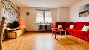 un soggiorno con divano rosso e TV di Apartment Alexandra - Handwerker willkommen, Parkplatz, Küche, WLAN a Malterdingen