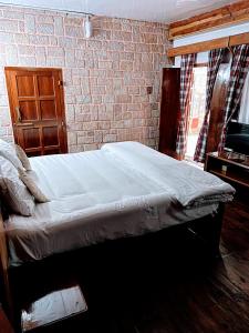 a bed in a bedroom with a brick wall at KEN & TWILL in Shillong