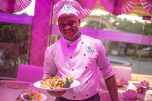 a man in a pink shirt holding a plate of food at Greenlight Hotel in Dar es Salaam