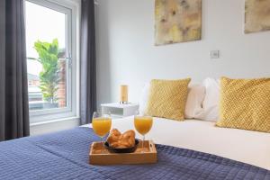 a bed with two glasses of orange juice and bread at Spacious 3 Bed Home in Cheltenham