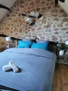 - une chambre avec un lit bleu et un mur en pierre dans l'établissement Gîte du Ligal, à Najac