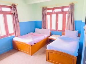 Dos camas en una habitación con paredes y ventanas azules. en HOTEL ICE VIEW POKHARA, en Pokhara