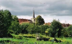 una iglesia con un campanario en medio de un campo en Pension "Am Tor zum Mainbogen", en Grettstadt