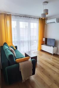 a living room with a green couch and a television at Apartament Olecko Centrum in Olecko