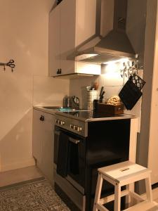a small kitchen with a stove and a stool at Rustic black and white studio in Helsinki