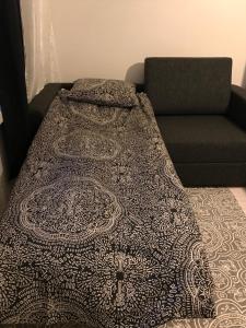 a bed with a comforter and a couch at Rustic black and white studio in Helsinki