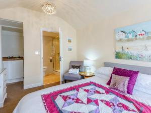 a bedroom with a bed with a pink blanket on it at Mikro Miramar - Cottage in Pevensey
