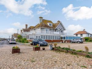 a large white house with cars parked in a parking lot at Mikro Miramar - Cottage in Pevensey