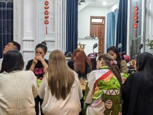 un grupo de personas sentadas alrededor de una mesa comiendo comida en ViLa Hà Huy Tập en Ấp Xuân An