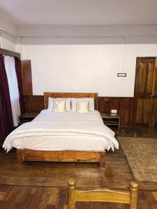 a bedroom with a large bed with white sheets at KEN & TWILL in Shillong