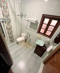 a bathroom with a toilet and a sink and a window at KEN & TWILL in Shillong