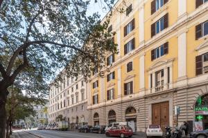 a large yellow building with cars parked on a street at Angelina Dimora Contemporanea in Rome