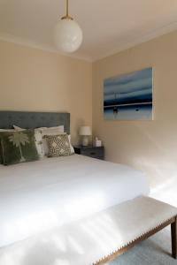 a bedroom with a large white bed and a painting at Woodland Bay Retreat-Luxury Hamptons Retreat in Lymington