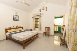 a bedroom with a bed and a chair and a window at Beach Village Holiday Homes Goa in Colva +59 photos