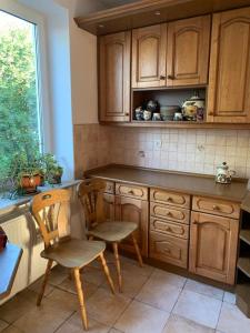 a kitchen with wooden cabinets and two chairs and a window at Apartament 65 m2 w centrum Łowicza in Łowicz