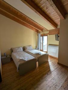 1 dormitorio con 2 camas en una habitación con suelo de madera en CONSTANCIA TRATTORIA, en Valdieri
