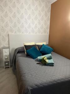 uma cama com almofadas azuis e flores em Moderno apartamento al lado del mar em Tacoronte