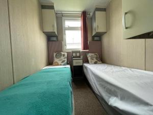 Duas camas num pequeno quarto com uma janela em Marine Holiday Park em Rhyl