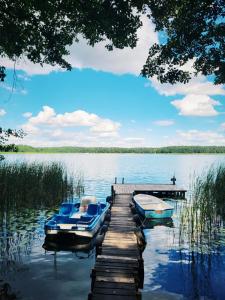two boats are docked at a dock on a lake at Dom nad jeziorem Mazury pomost segment 1 in Kozin