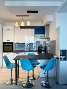 una cocina con sillas azules y una mesa negra en Apartament z widokiem na panoramę Gdyni w Modern Tower ATAL, en Gdynia