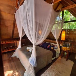 a bedroom with a canopy bed with a white curtain at Casa Embira - 300 metros da Praia do Lago Verde in Alter do Chao