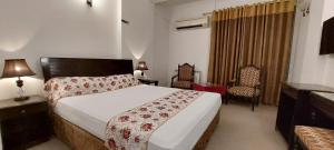 a bedroom with a bed and chairs in a room at Grace Crown Hotel in Rawalpindi