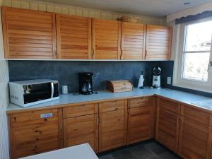 eine Küche mit Holzschränken und einer Mikrowelle auf der Theke in der Unterkunft Villa Bon Temps Durbuy in Durbuy