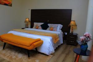 1 dormitorio con 1 cama grande y asiento naranja en Mamikki Farm and Cottages, en Tororo