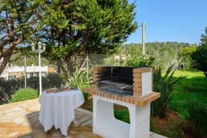 Villa Cas Puig - Beach of Portinatx في بورتينانكس: شواية في الهواء الطلق مع طاولة على الفناء