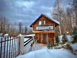 a log cabin in the snow with a sign on it at Chalet Nomad in Petroşani