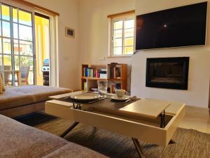 een woonkamer met een salontafel en een flatscreen-tv bij Homefield Gardens by HnM in Conceição