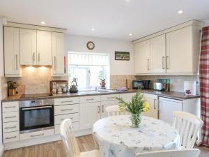 a kitchen with white cabinets and a table with chairs at Bear Lake Lodge in Alderwasley