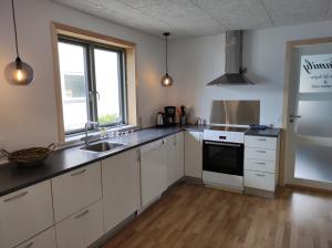 una cucina con armadi bianchi e lavandino di Hjortdal B&B a Fjerritslev