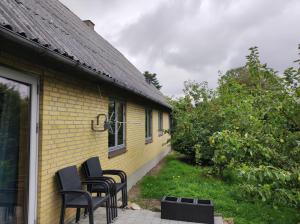 a group of chairs sitting outside of a yellow house at Hjortdal B&B in Fjerritslev