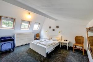 1 dormitorio con 1 cama blanca y 2 sillas en Vakantiehuis Nordseezauber - Callantsoog, en Callantsoog