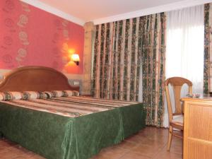 a bedroom with a bed and a chair in it at Hotel Las Ruedas in Laredo