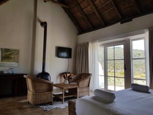 a bedroom with a bed and chairs and a television at Karoo 1 Hotel Village in De Doorns