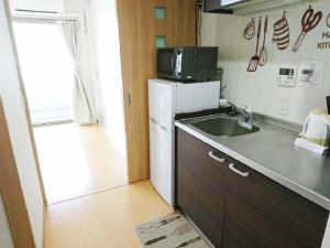 una pequeña cocina con fregadero y microondas en abc OSAKA en Osaka